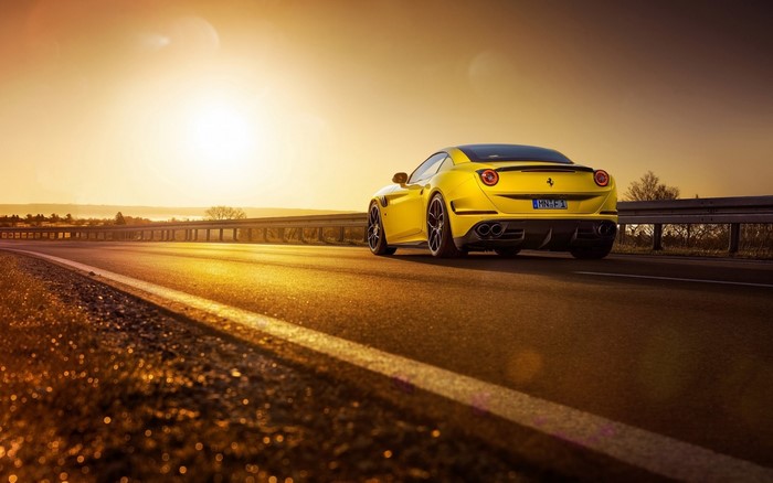 Yellow Ferrari California T on a road at sunset