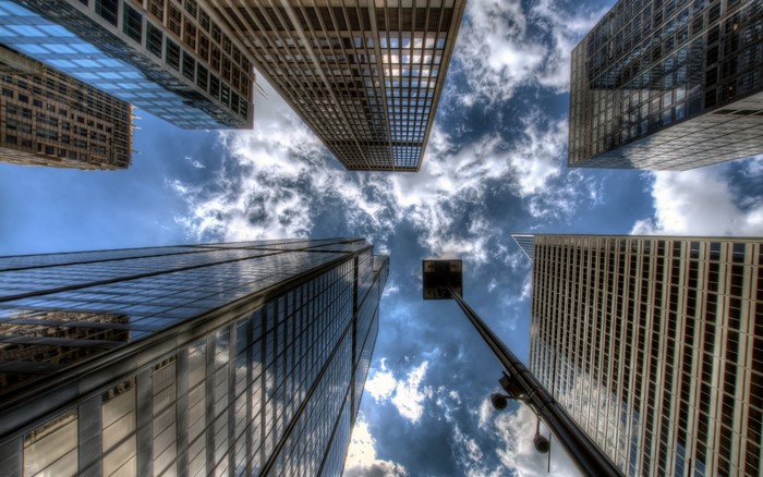 Looking up at skyscrapers against a cloudy sky