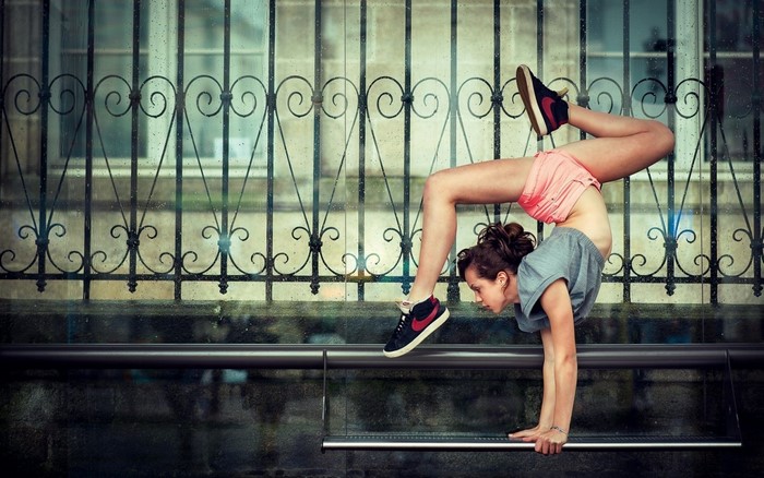 Woman performing a handstand in front of a fence