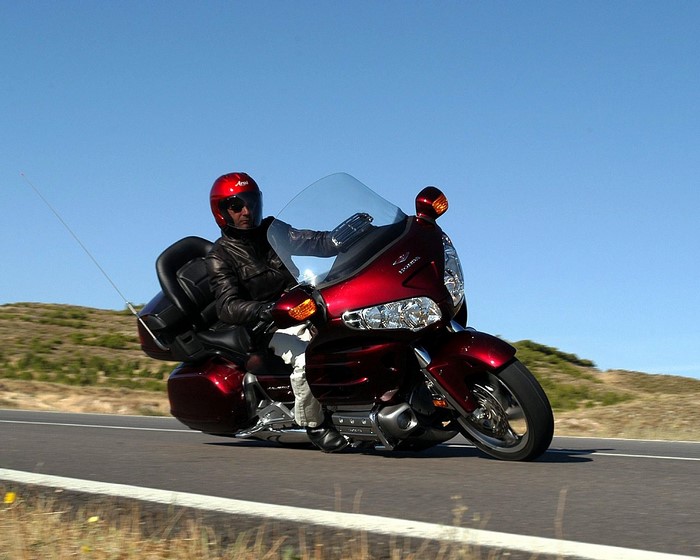 Man riding a red Honda Goldwing motorcycle on a road