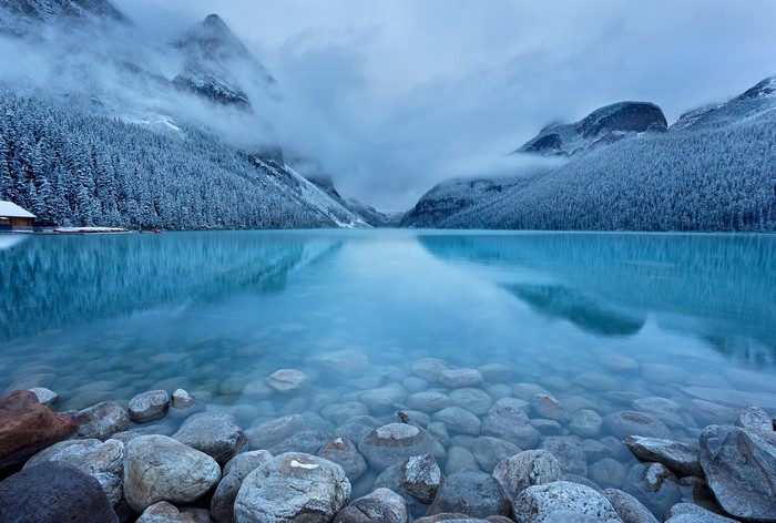 Turquoise lake with snow-covered mountains and forest