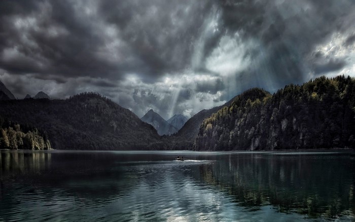 Boat on a lake with mountains and stormy clouds