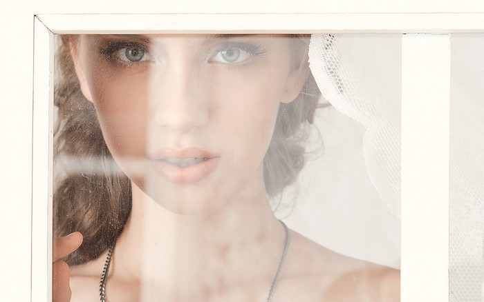 Woman looking through a window with sheer fabric