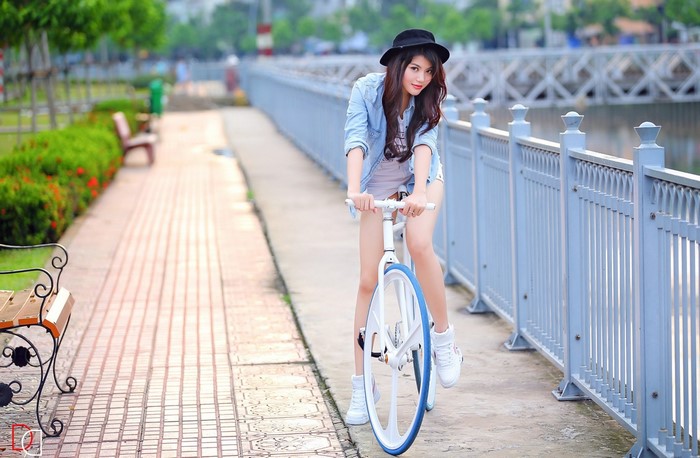 Asian woman in hat riding a bicycle outdoors