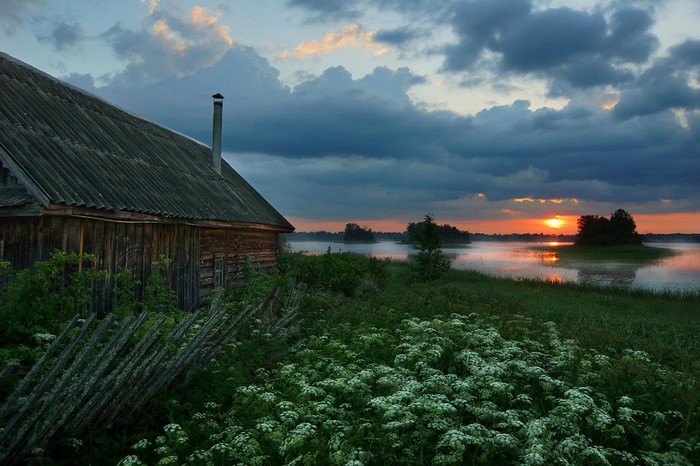 Wooden house by a lake at sunset