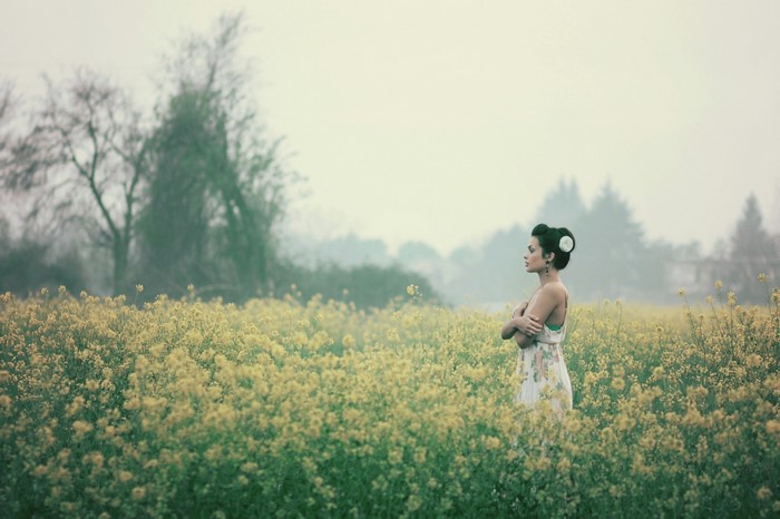 Woman in a floral dress in a field of yellow flowers