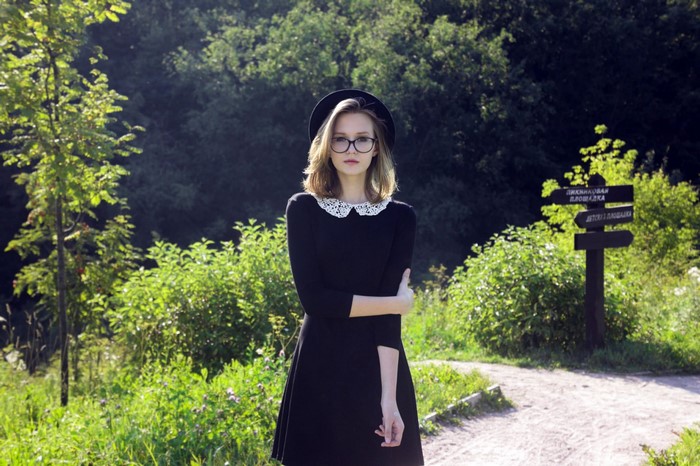 Woman in black dress and hat in a forest