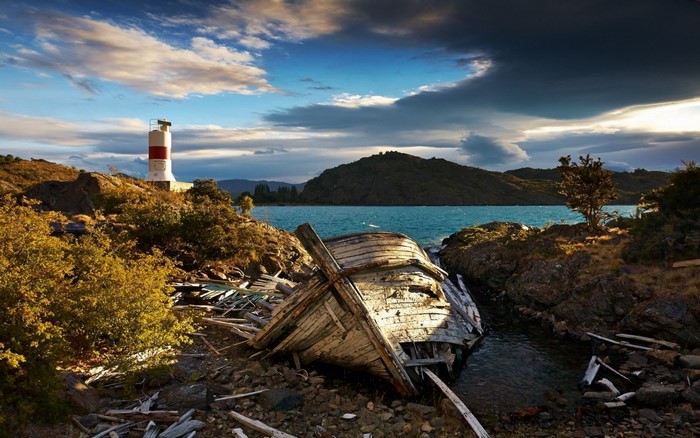 Shipwreck and lighthouse on a rocky coast