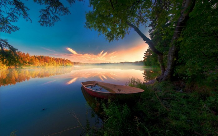 Boat on a misty lake at sunrise with autumn trees
