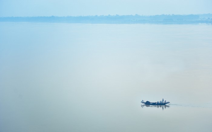 Boat with people on a misty river at dawn