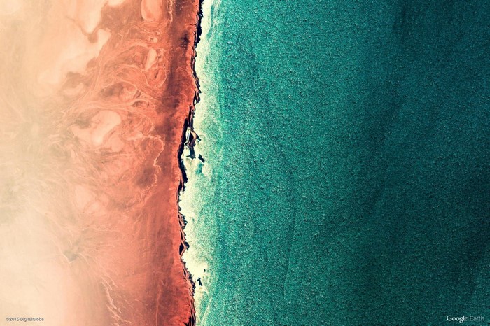 Aerial view of a coastline with red sand and turquoise water