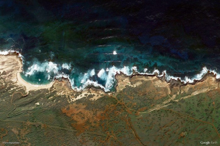 Aerial view of a rocky coastline with waves and vegetation