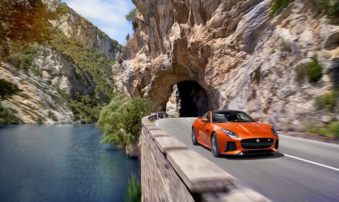 Orange Jaguar F-Type SVR driving through a mountain tunnel