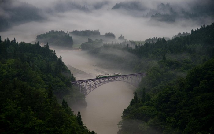 Train crossing a bridge over a misty river valley