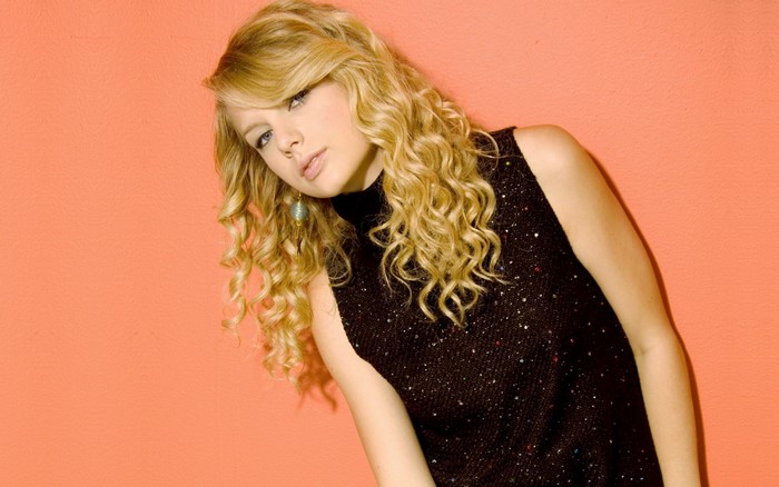 Taylor Swift posing against an orange background