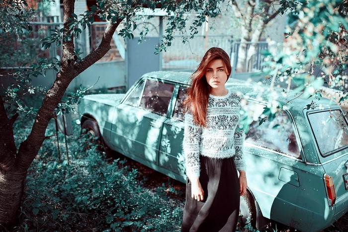 Woman standing next to an old car