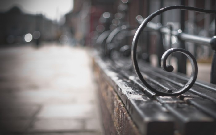 Close-up of a metal bench with bokeh background