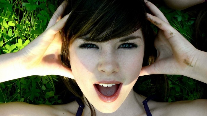 Woman with hands on head lying in grass