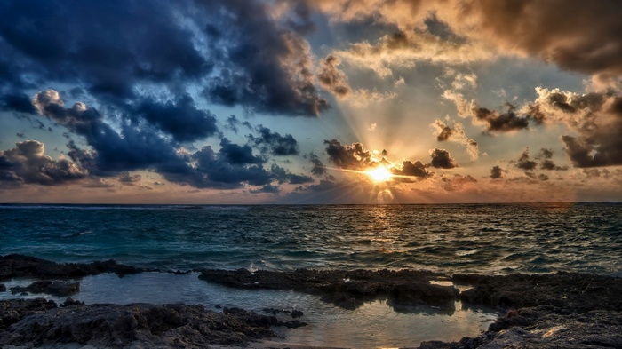 Sunset over the ocean with rocky shore