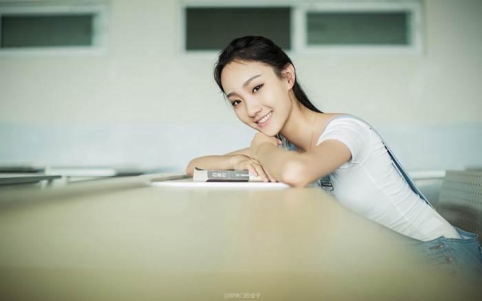 Young Asian woman sitting at a desk with a book