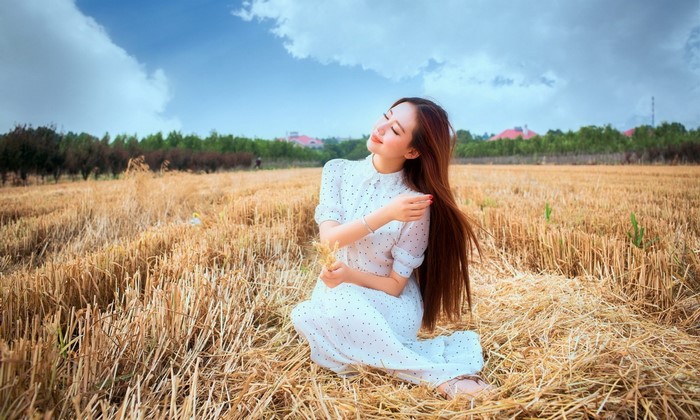 Woman in a white polka dot dress in a wheat field