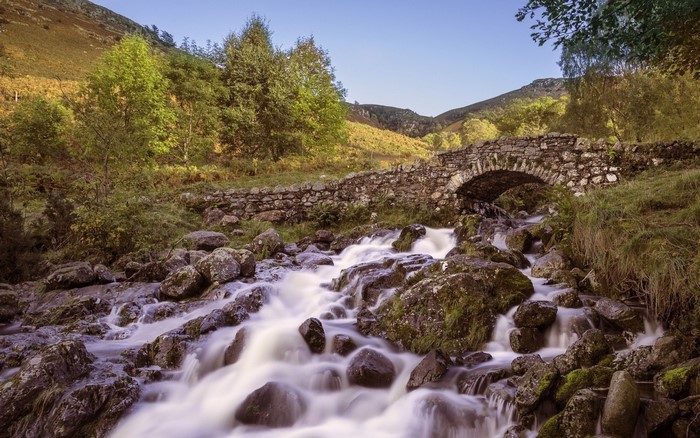 Stone bridge over a rocky stream in a mountain valley