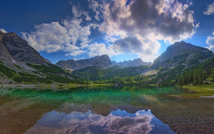 Alpine lake with mountains and clouds reflection