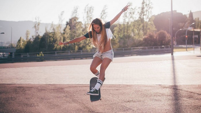 Woman skateboarding outdoors in sunlight