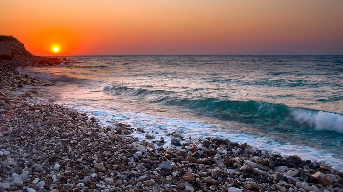 Sunset over a rocky beach and ocean waves