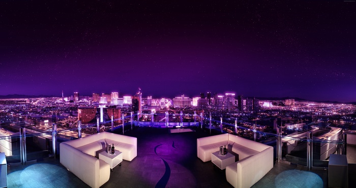 Rooftop lounge overlooking a neon city at night