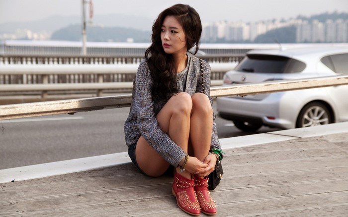 Clara Lee Sitting Outdoors in Fashionable Attire