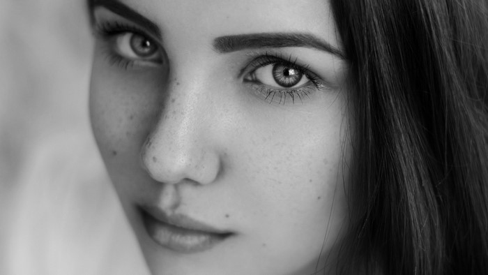 Monochrome close-up portrait of a young woman with freckles