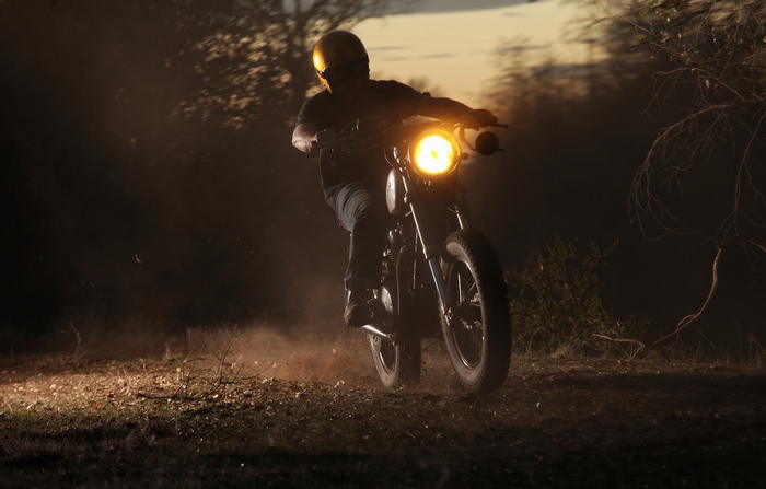 Motorcyclist in a yellow helmet riding a motorcycle at dusk