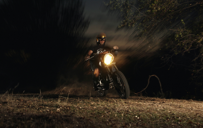 Man riding a motorcycle at night in a forest