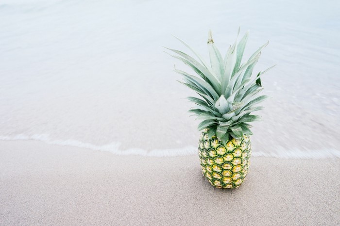 Pineapple on a sandy beach with gentle waves