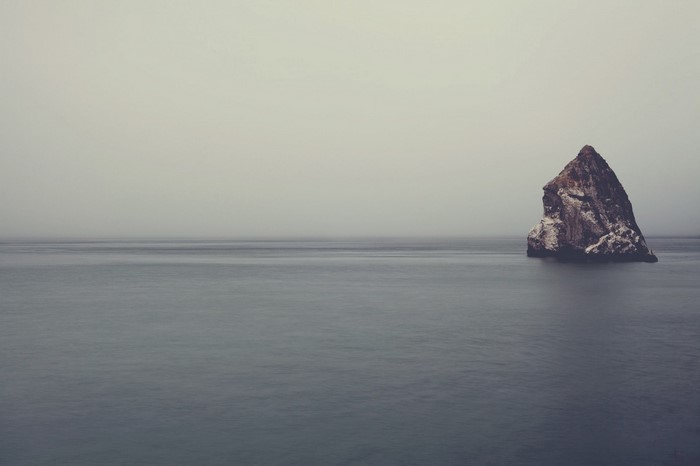 Rock formation in the sea under a foggy sky