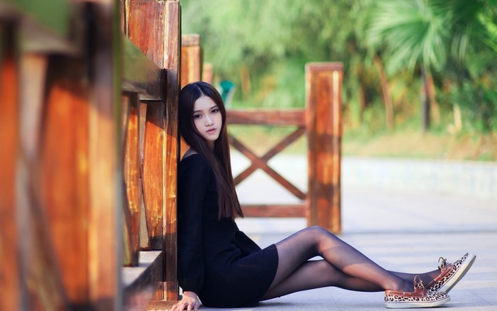Elegant Woman in Black Dress Sitting Outdoors