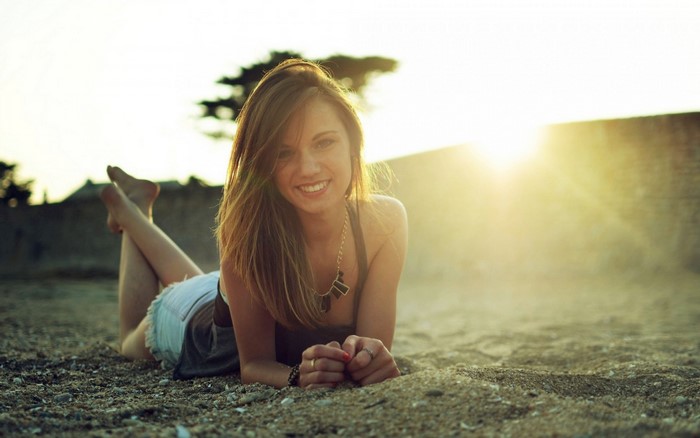 Woman lying on sand with sun rays