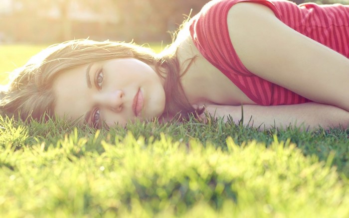 Woman lying on grass in sunlight