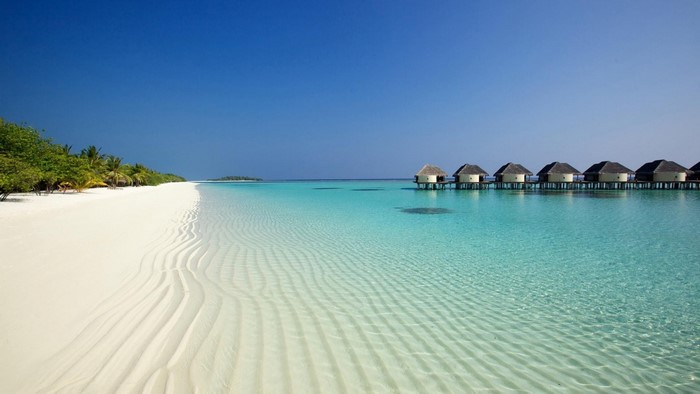 Tropical beach with overwater bungalows and clear turquoise water