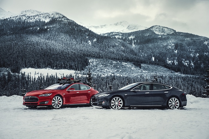 Two Tesla Model S cars in a snowy mountain landscape