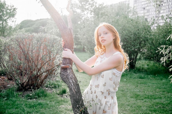 Redhead woman in a dress holding a tree outdoors