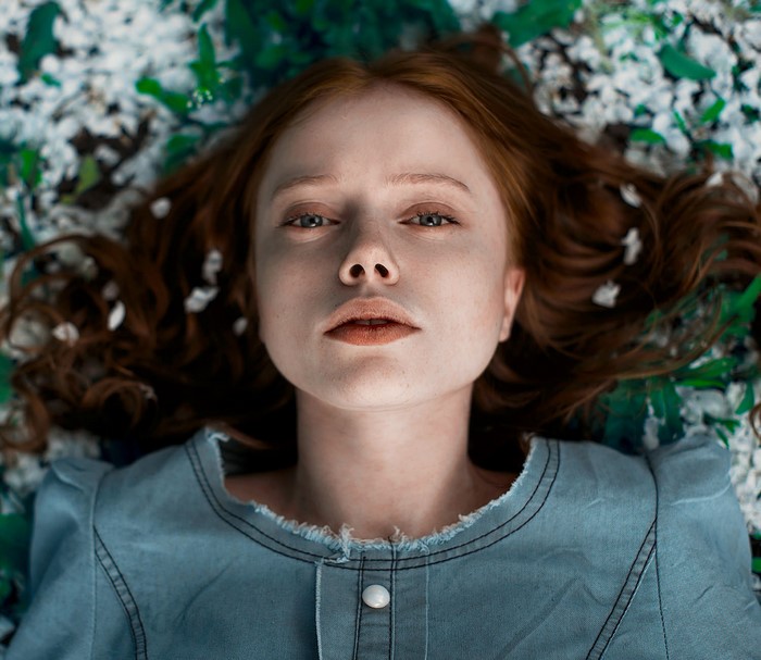 Redhead woman lying down with flowers and leaves