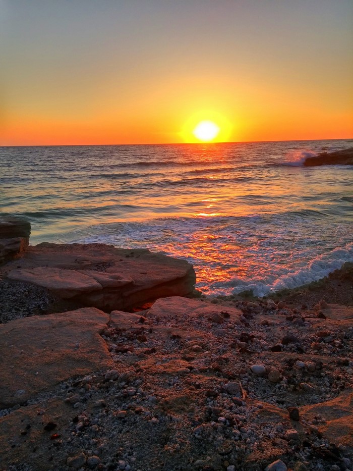 Sunset over the sea with rocky shore