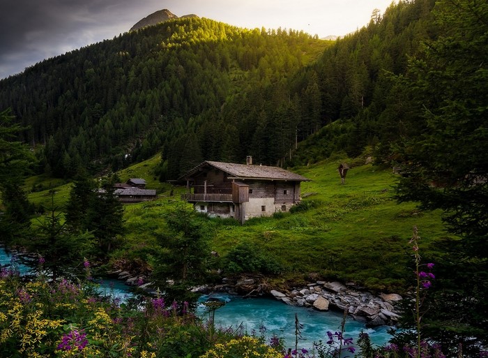 Wooden cottage by a turquoise river in the Alps
