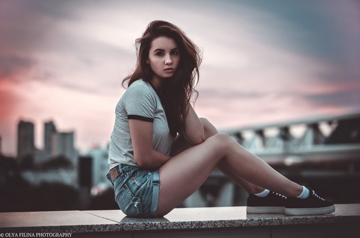 Woman in jean shorts and striped t-shirt sitting outdoors