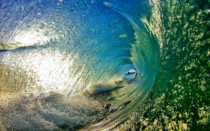 Inside a wave barrel with sunlight and ocean water