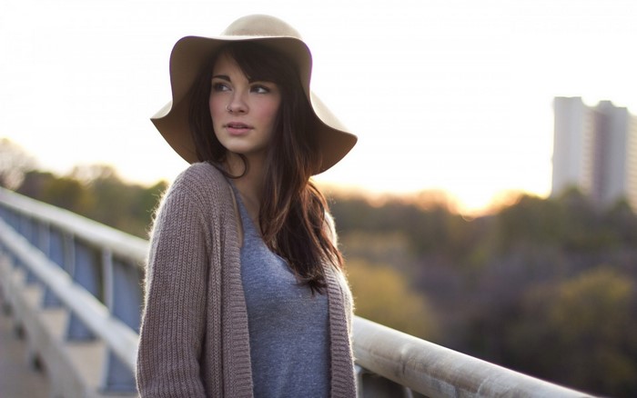 Woman wearing a hat and cardigan on a bridge