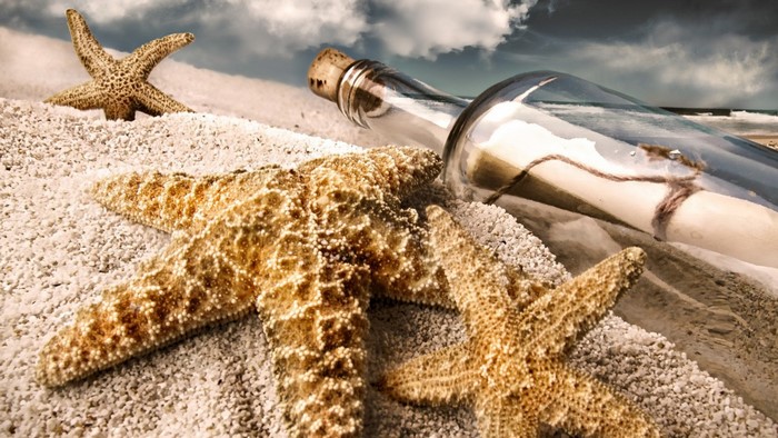 Message in a bottle with starfish on a sandy beach