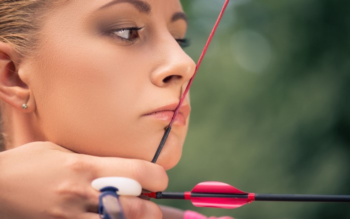 Woman aiming a recurve bow with an arrow